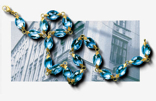 Blue beaded necklace with gold accents on a newspaper background