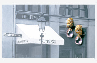 Gold earrings with pink stones displayed in front of a store named Fochtman on Maximiliansstrasse in Munich.