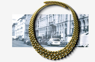 Gold necklace with beads in front of a black and white cityscape