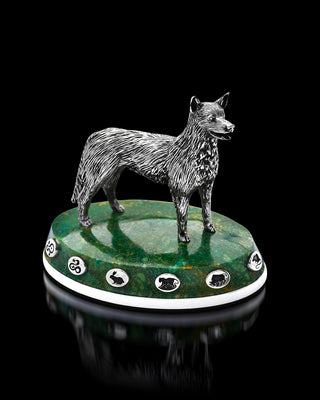 Dog figurine on a green and white base with symbols against a black background