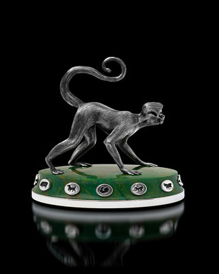 Decorative monkey figure on a green base with emblemstones against a black background