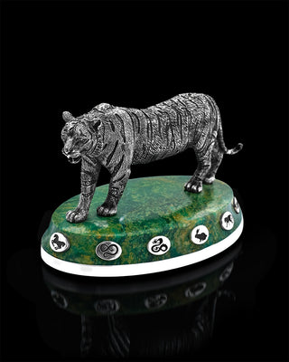 Silver tiger figurine on a green marble base with symbols against a black background